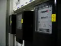 Rząd czarnych liczników energii elektrycznej. Na pierwszym liczniku widoczny odczyt 3104577 kWh.