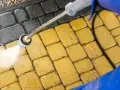 Mycie kostki brukowej myjką ciśnieniową. Woda pod ciśnieniem skutecznie usuwa brud, pokazując, czym wyczyścić kostkę brukową.