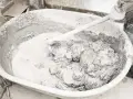 Mieszanie wapna palonego z wodą w dużej misie, tworząc gęstą, szarą masę.