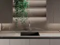 Nowoczesna kuchnia z blatem i płytą backsplash z kamienia, przypominającego marmur. Wisząca zieleń dodaje życia.