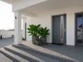 Nowoczesne drzwi wejściowe z roślinami w donicach. Poradnik: jak wyregulować drzwi wejściowe.