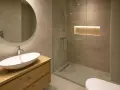 Ciepła, subtelna barwa światła w łazience podkreśla drewniane akcenty i tworzy relaksującą atmosferę.