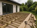 Budowa tarasów z deski kompozytowej w toku. Widoczna konstrukcja nośna i materiały do wykończenia.