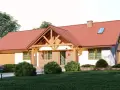 Dom w stylu kolonialnym z czerwoną dachówką, ceglanymi elementami i drewnianą werandą.