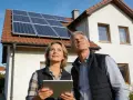 Para z tabletem analizuje instalację fotowoltaiczną 5 kW cena z montażem na dachu domu.