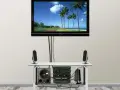 Nowoczesny telewizor z widokiem na plażę, pod nim sprzęt audio i głośniki. Całość wygląda jak idealny kanał telewizyjny podtynkowy.