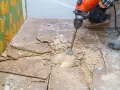 Skuwanie płytek cena: robotnik z młotem udarowym usuwa stare płytki z podłogi.