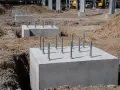 Solidne fundamenty z żelbetonu z wystającymi śrubami czekają na konstrukcję.