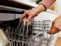 Ręce wkładają szklanki do zmywarki. To część poradnika, jak wybrać zmywarkę, pokazująca praktyczne użycie.