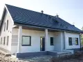 Nowy dom z szarą dachówką i jasną elewacją, gotowy do malowania. Eleganckie wykończenie podkreśla nowoczesny styl.