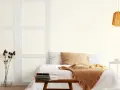Sypialnia z łóżkiem, narzutą i poduszkami. Wazon z suszonymi kwiatami i lampa w stylu cloud dancer.