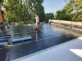 Pracownik wykonuje hydroizolację tarasu nad garażem, używając palnika do papy.