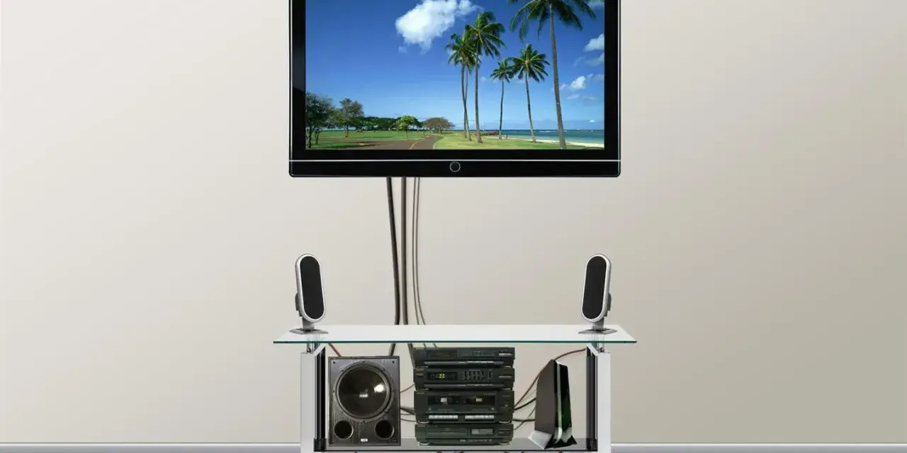 Nowoczesny telewizor z widokiem na plażę, pod nim sprzęt audio i głośniki. Całość wygląda jak idealny kanał telewizyjny podtynkowy.