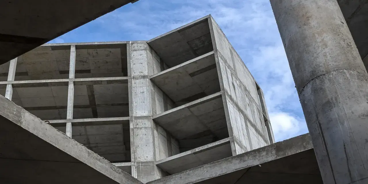 Szkielet budynku z betonu, widok od dołu na niebo. Konstrukcja z betonu, jakby z **styrobetonu**, czeka na wykończenie.