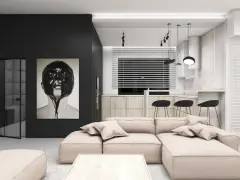 Nowoczesny salon w stylu minimalistycznym. Duża, beżowa kanapa, obraz z twarzą w czarnej farbie, kuchnia z drewnianymi frontami i czarnymi hokerami.
