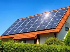 Instalacja fotowoltaiczna 10 kW cena z montażem na dachu domu pod błękitnym niebem.