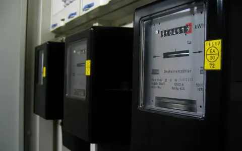 Rząd czarnych liczników energii elektrycznej. Na pierwszym liczniku widoczny odczyt 3104577 kWh.
