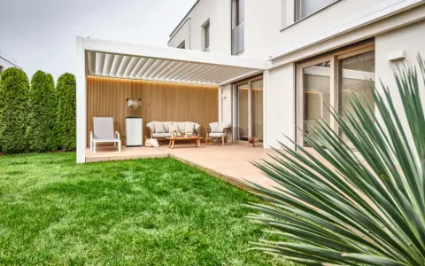 Drewniana ściana i żywopłot to pomysły, czym zabudować boki tarasu, tworząc przytulną przestrzeń.