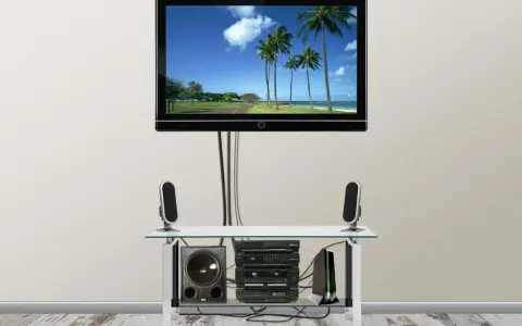 Nowoczesny telewizor z widokiem na plażę, pod nim sprzęt audio i głośniki. Całość wygląda jak idealny kanał telewizyjny podtynkowy.