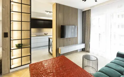 Nowoczesny, bardzo mały salon w bloku z otwartą kuchnią, drewnianymi panelami i designerskimi meblami.