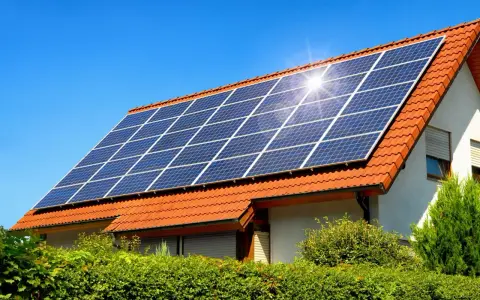Instalacja fotowoltaiczna 10 kW cena z montażem na dachu domu pod błękitnym niebem.