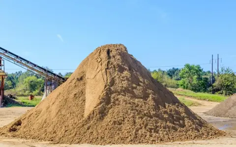 Ogromna hałda piasku na placu budowy. Zastanawiasz się, ile kosztuje tona piasku? Tu jest odpowiedź, choć cena może się różnić.