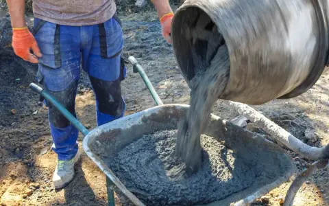 Robotnik wylewa beton B25 z betoniarki do taczki. Sprawdzamy beton b25 cena za m3.