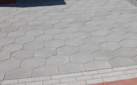 Szara, sześciokątna trelinka tworzy wzór na chodniku.