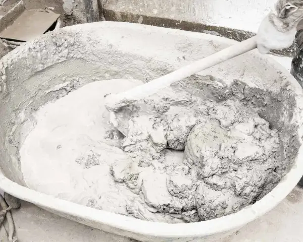 Mieszanie wapna gaszonego z wodą w dużej misie, tworząc gładką masę do tynkowania.