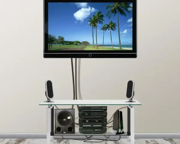 Nowoczesny telewizor z widokiem na plażę, pod nim sprzęt audio i głośniki. Całość wygląda jak idealny kanał telewizyjny podtynkowy.