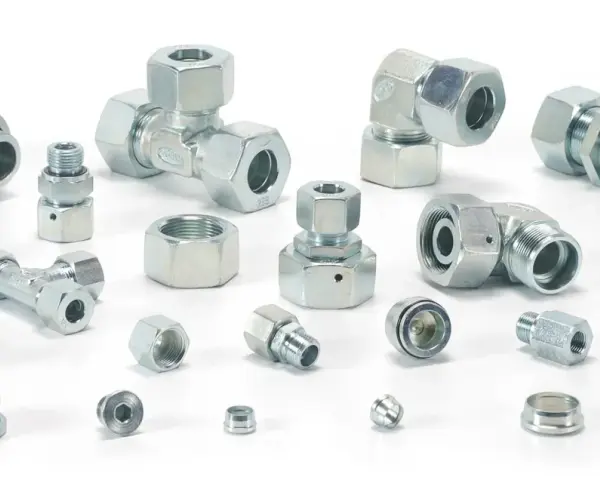 Różnorodne metalowe elementy hydrauliczne, w tym trójniki, kolanka i złączki, tworzą skomplikowany śrubunek.