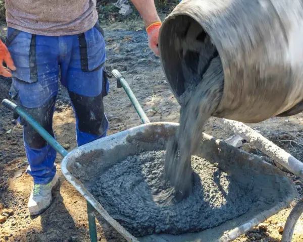 Robotnik wylewa beton B25 z betoniarki do taczki. Sprawdzamy beton b25 cena za m3.