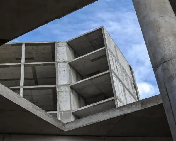 Szkielet budynku z betonu, widok od dołu na niebo. Konstrukcja z betonu, jakby z **styrobetonu**, czeka na wykończenie.