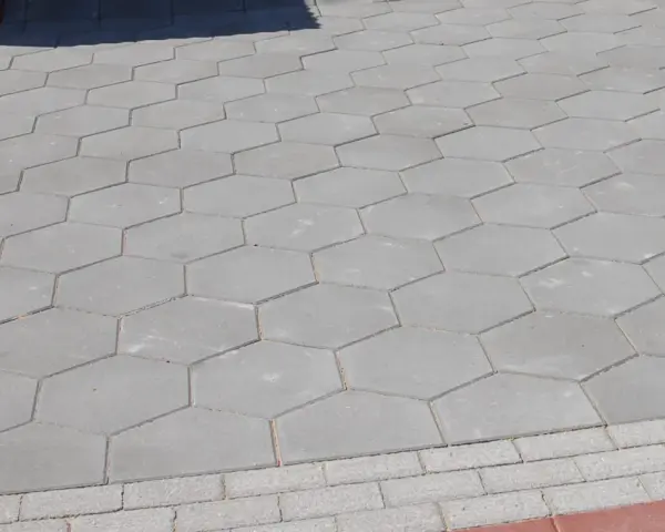 Szara, sześciokątna trelinka tworzy wzór na chodniku.