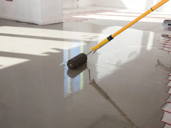 Wylewki anhydrytowe cena za 1m2. Wałek dociskowy rozprowadza świeżą masę po podłodze z ogrzewaniem podłogowym.