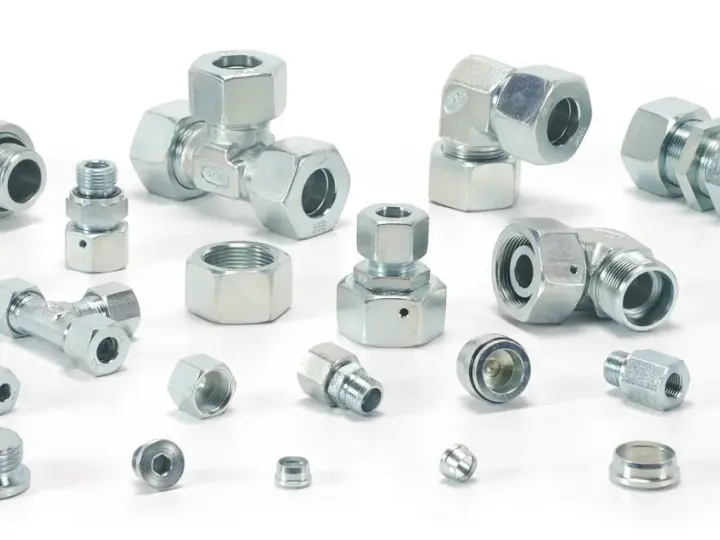 Różnorodne metalowe elementy hydrauliczne, w tym trójniki, kolanka i złączki, tworzą skomplikowany śrubunek.