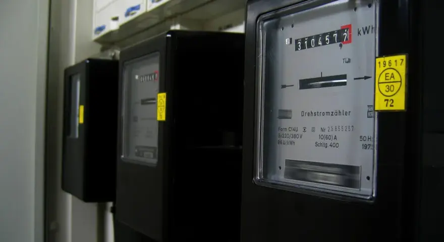 Rząd czarnych liczników energii elektrycznej. Na pierwszym liczniku widoczny odczyt 3104577 kWh.