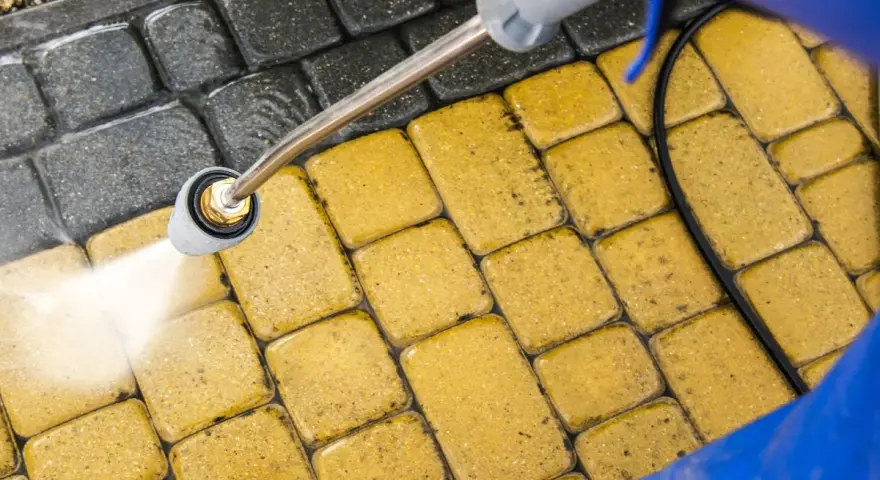 Mycie kostki brukowej myjką ciśnieniową. Woda pod ciśnieniem skutecznie usuwa brud, pokazując, czym wyczyścić kostkę brukową.
