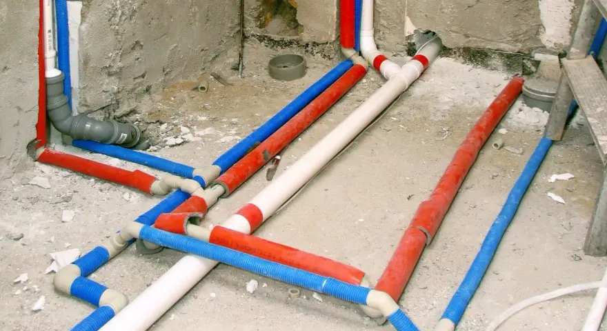 Skomplikowana instalacja wodna z rurami w kolorach czerwonym, niebieskim i białym, przygotowana do tynkowania.