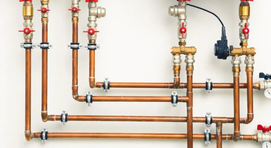 System hydrauliczny z miedzianymi rurami i zaworami. Różnica między złączkami PEX U czy TH jest kluczowa dla szczelności instalacji.