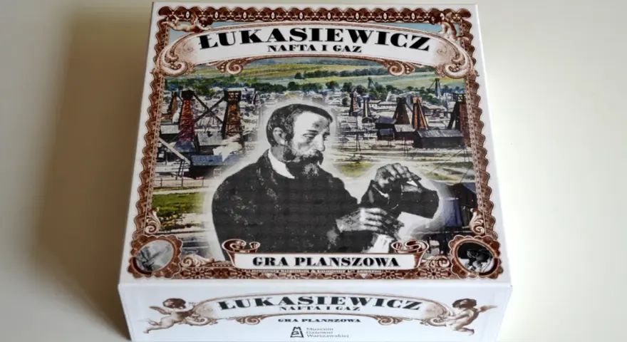 Pudełko gry planszowej "Łukasiewicz: Nafta i Gaz" z Ignacym Łukasiewiczem na tle szybów naftowych.