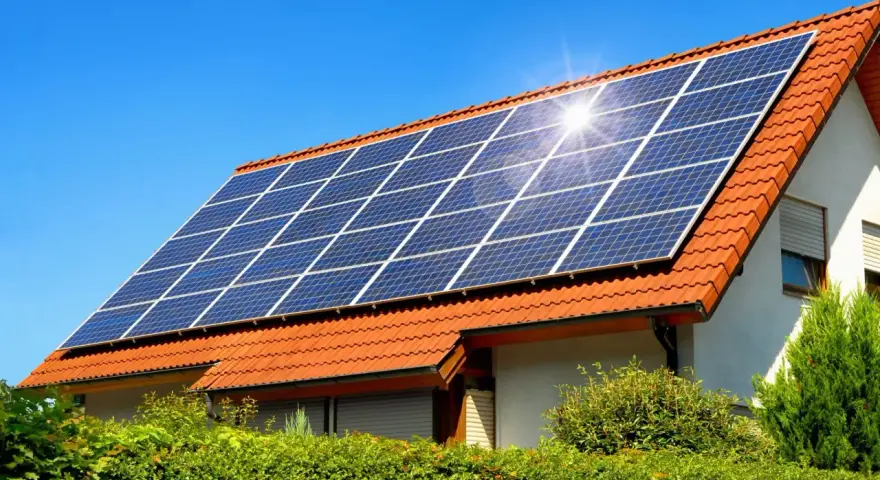 Instalacja fotowoltaiczna 10 kW cena z montażem na dachu domu pod błękitnym niebem.