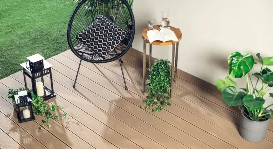 Drewno kompozytowe to świetny pomysł, czym wyłożyć balkon. Wygodne krzesło, stolik i rośliny tworzą przytulną przestrzeń.