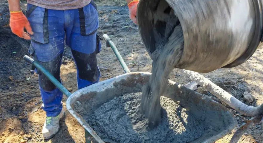Robotnik wylewa beton B25 z betoniarki do taczki. Sprawdzamy beton b25 cena za m3.