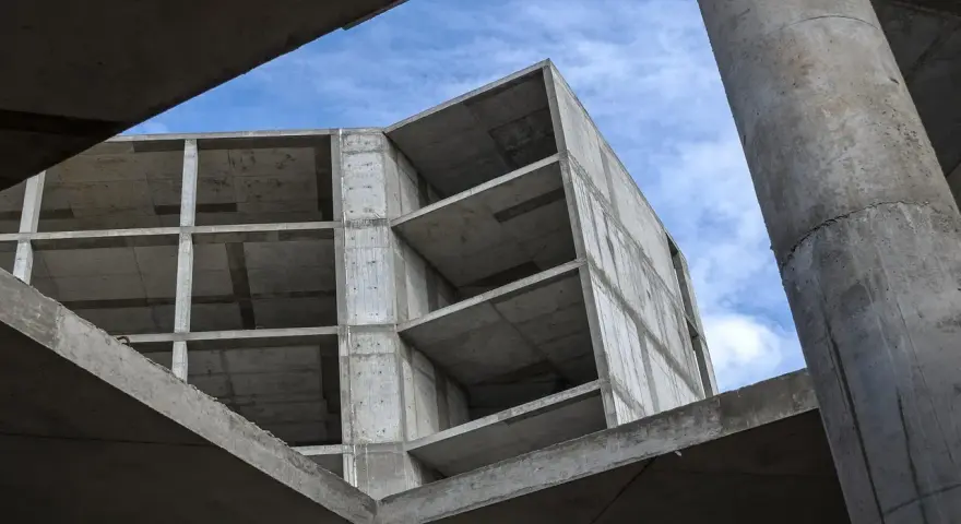 Szkielet budynku z betonu, widok od dołu na niebo. Konstrukcja z betonu, jakby z **styrobetonu**, czeka na wykończenie.