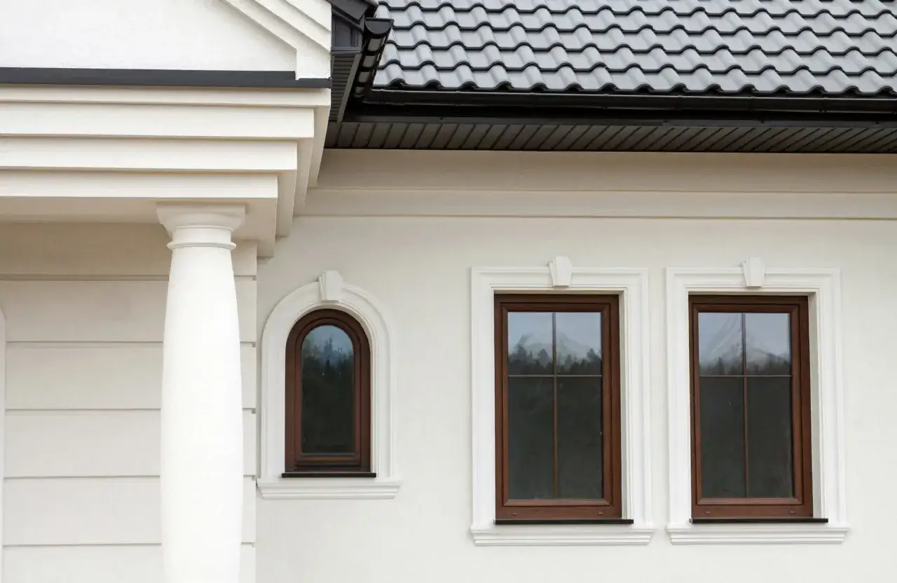 Elegancki gzyms zdobi fasadę domu, podkreślając klasyczny styl okien i kolumn.