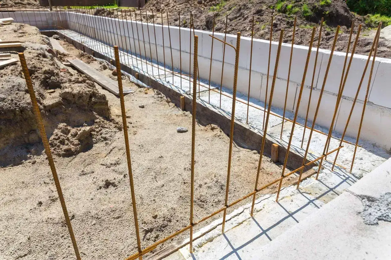 Budowa fundamentów: zbrojenie i szalunki z bloczków betonowych czekają na zalanie, by stworzyć solidny żelbeton.