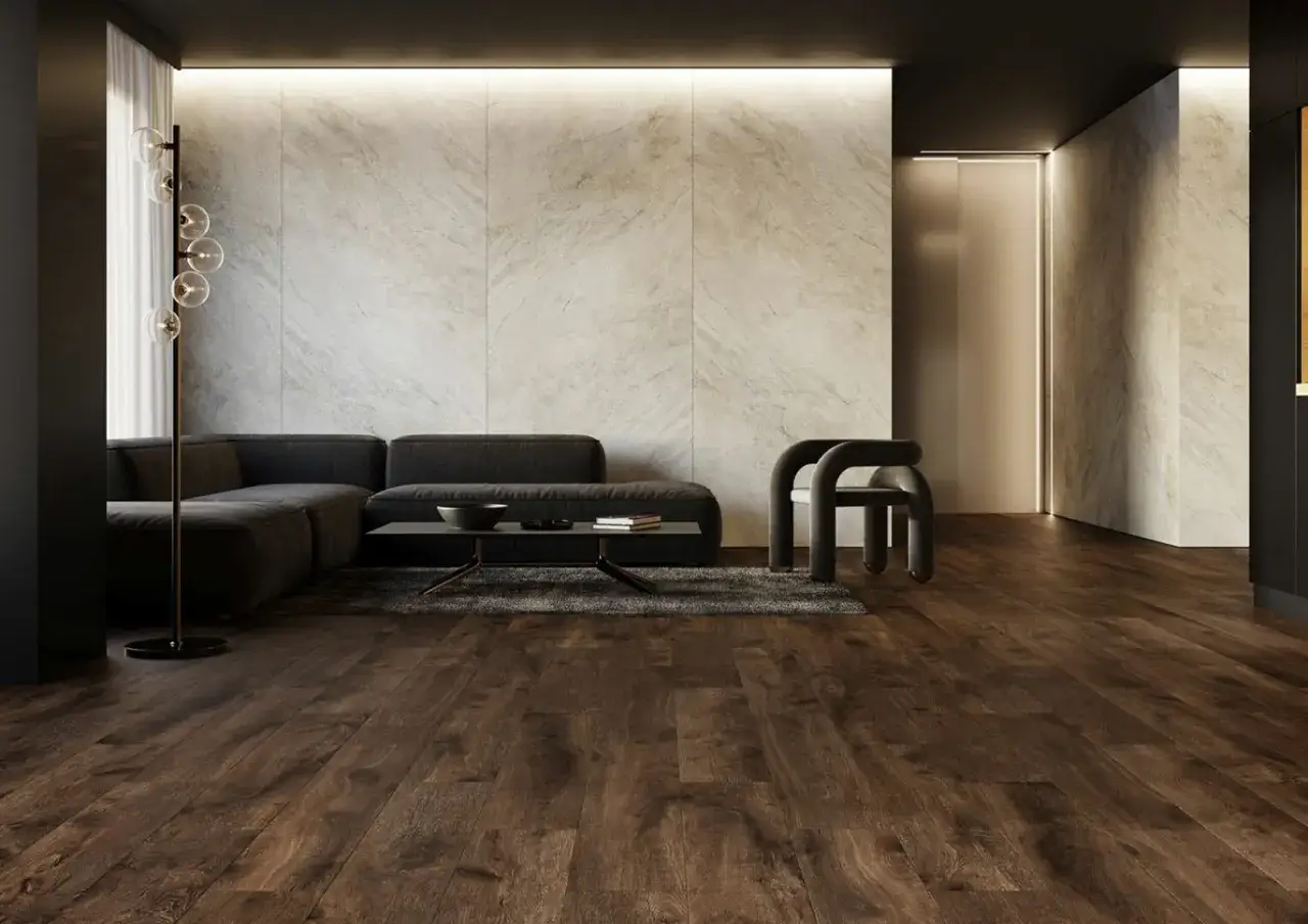 Nowoczesny salon z ciemnym drewnem na podłodze, szarą kanapą, designerskim fotelem i kamienną ścianą.