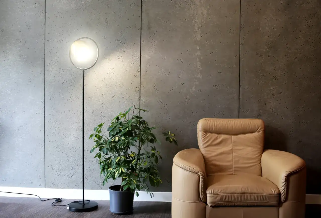 Nowoczesny salon z fotelem i lampą stojącą na tle ściany z betonu 77.