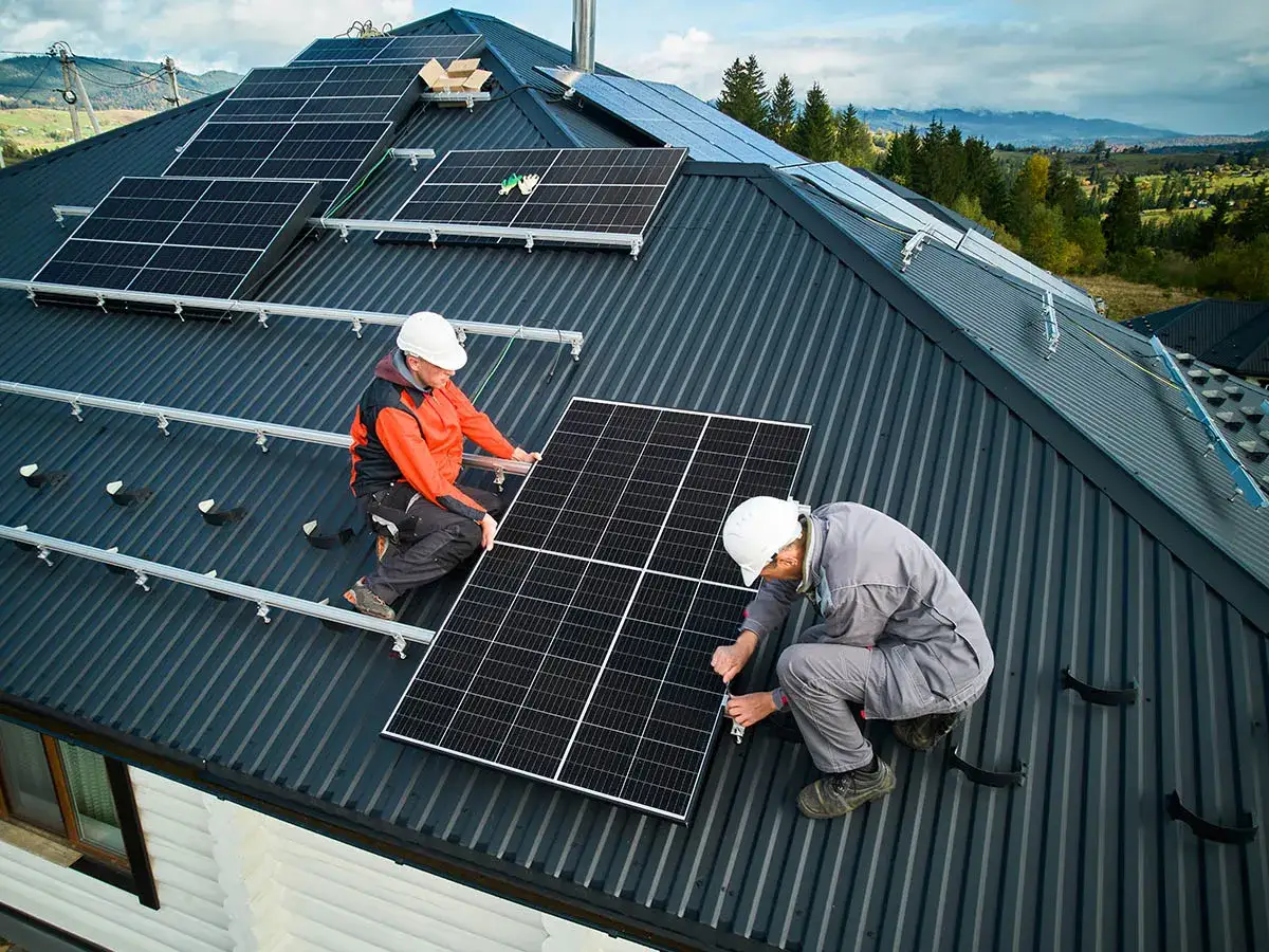 Instalacja fotowoltaiczna 5 kW cena z montażem. Dwóch monterów na dachu instaluje panele słoneczne.